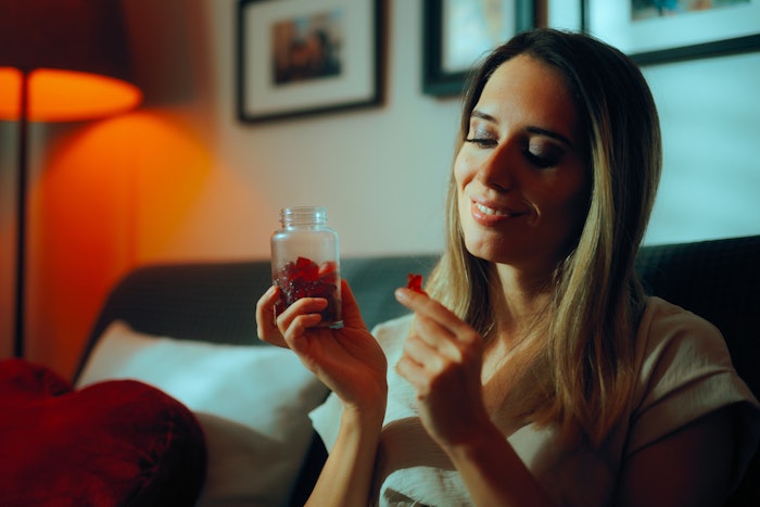 Woman Taking Gummy Suipplement Adobe Stock 1033034872