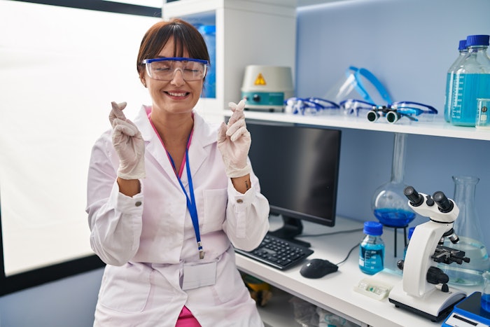 Chemist In Lab Fingers Crossed Eyes Closed Smiling Adobe Stock 542206955