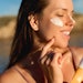 Woman Applying Sunscreen Outside Beach Sunlight Holding Product Adobe Stock 1566888505