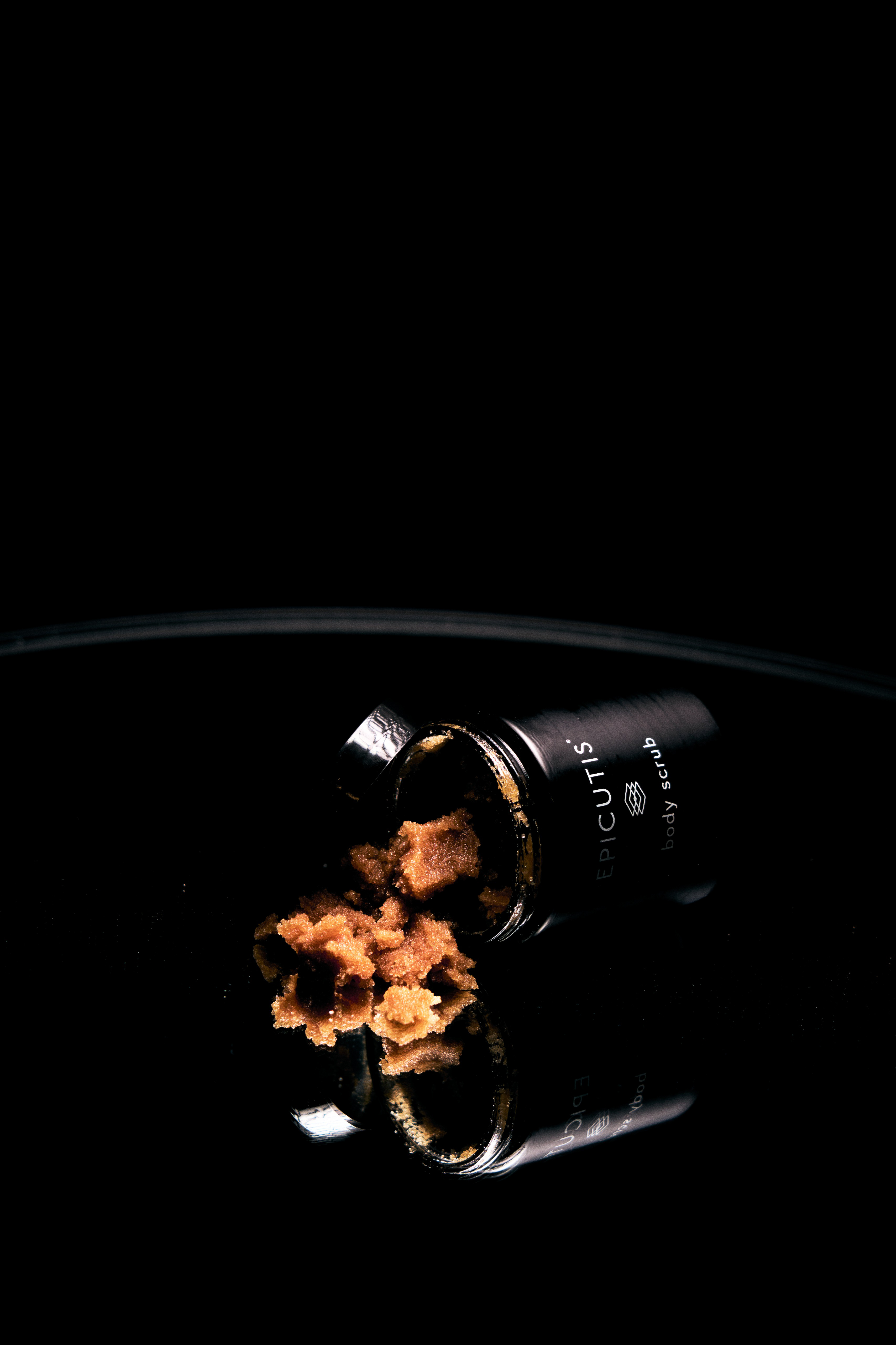 Epicutis skincare jar spilling golden-bronze powder or supplement on black background