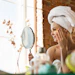 Woman applying gold eye patches while looking in mirror during skincare routine