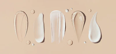 Skincare product textures and formulations displayed on beige background with droplets