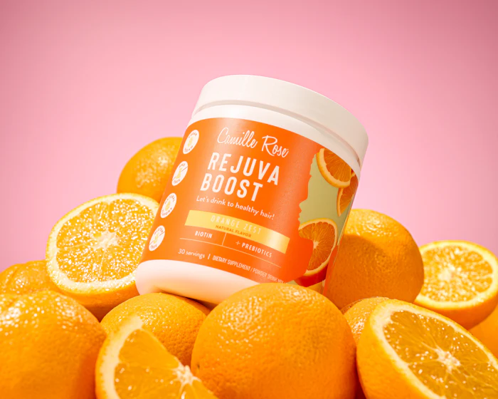 Camilla Raw Rejuva Boost hair supplement jar surrounded by fresh oranges on pink background