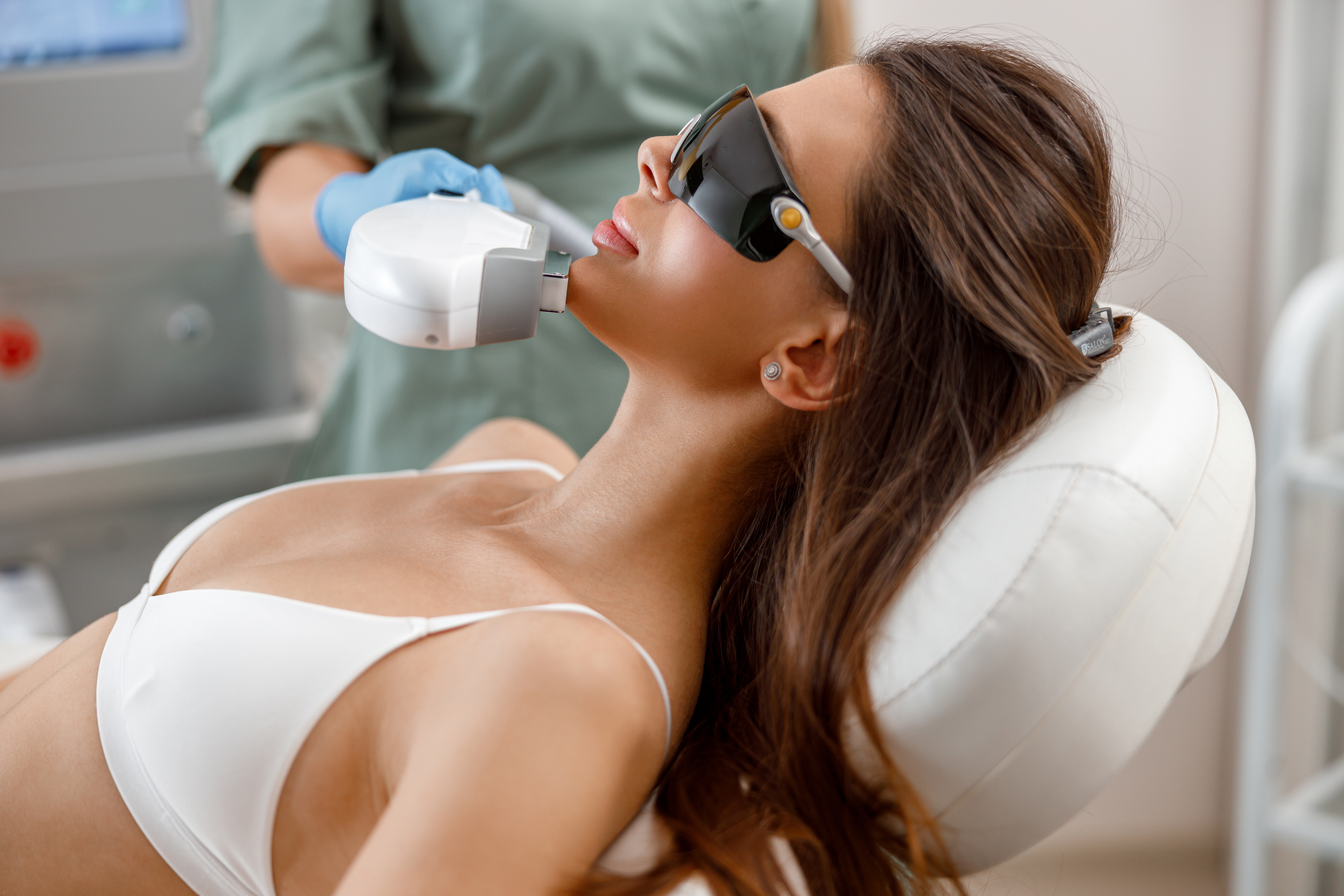 Woman receiving laser hair removal or skin treatment at aesthetic clinic with protective eyewear