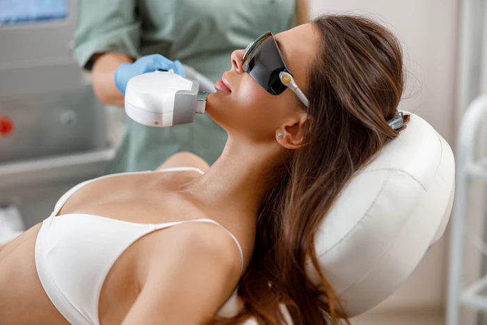 Woman receiving laser hair removal or skin treatment at aesthetic clinic with protective eyewear