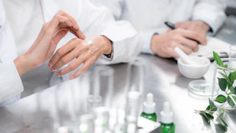 Scientists in lab coats examining skincare products and botanical samples in a laboratory setting