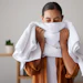 Woman wrapping white towel around herself in spa setting wearing brown robe