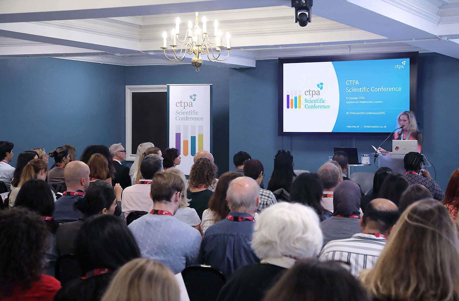 Audience members attending CTPA Scientific Conference presentation with speaker at podium and branded signage