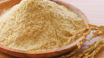 Fine wheat flour in wooden bowl with golden wheat stalks on neutral background